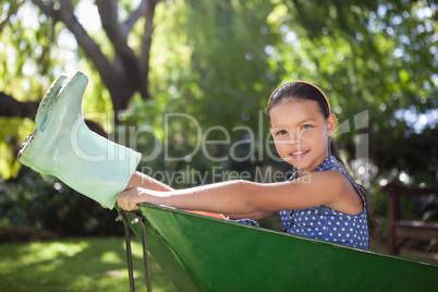 Portrait of girl sitting in wheelbarrow at backyard