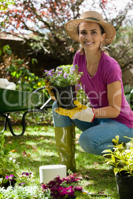 Portrait of smiling woman holding potted plant in backyard