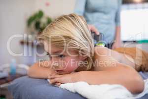 Close-up of boy lying on bed while female therapist using ultrasound machine