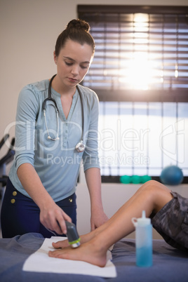 Young female therapist scanning feet of boy lying on bed