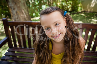 High angle portrait of smiling girl sitting on wooden bench