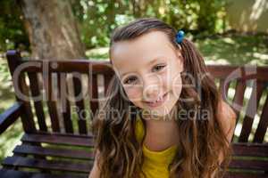 High angle portrait of smiling girl sitting on wooden bench