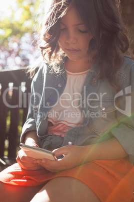 Girl using mobile phone while sitting on bench