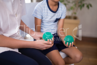 Midsection of female therapist and boy holding stress balls