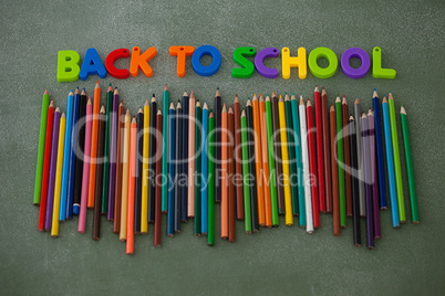 Block letters and color pencils arranged on chalkboard