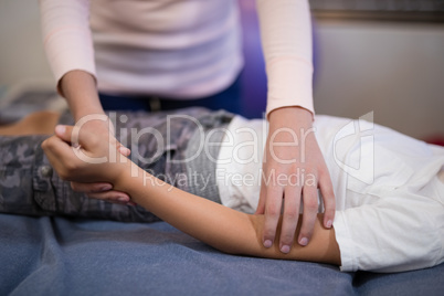 Close-up of female therapist examining hand while boy lying on bed Close-up of female therapist examining hand while boy lying on bed