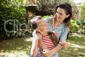 Smiling woman and daughter enjoying while standing against trees