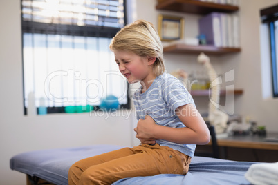 Boy sitting on bed with stomachache