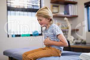 Boy sitting on bed with stomachache