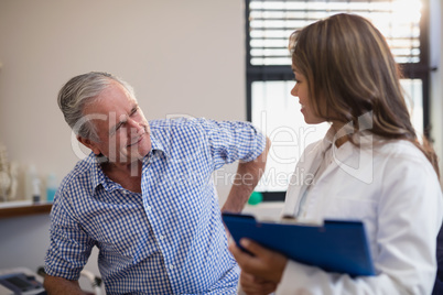 Senior male patient showing back ache to female doctor with file