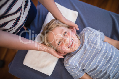 High angle portrait of smiling smiling boy receiving massage from female physiotherapist