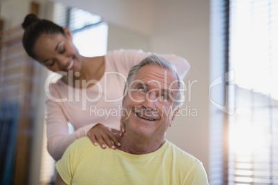 Smiling senior male patient receiving neck massage from therapist