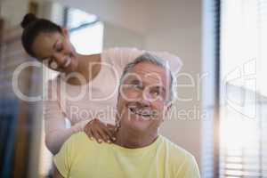 Smiling senior male patient receiving neck massage from therapist