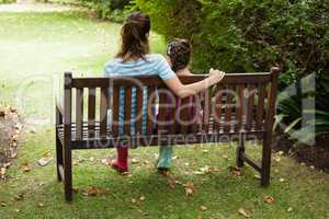 Rear view of woman and girl sitting on wooden bench