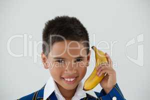 Schoolboy holding banana against white background