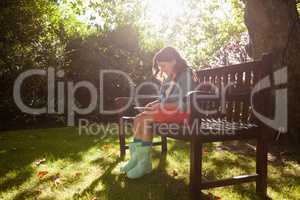 Smiling girl using smart phone on wooden bench