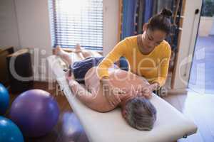 High angle view of shirtless senior male patient receiving neck massage from female therapist
