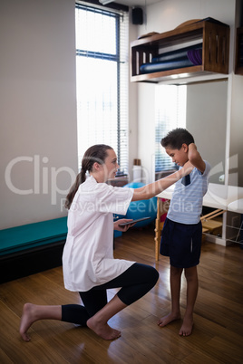 Side view of female therapist kneeling while examining boy