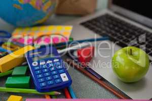 Various school supplies, apple and laptop on chalkboard