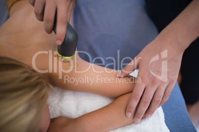High angle view of female therapist using ultrasound machine on shoulder