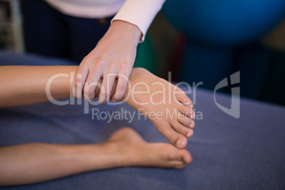 High angle view of female therapist examining feet with boy lying on bed