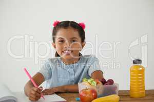 Schoolgirl doing her homework against white background