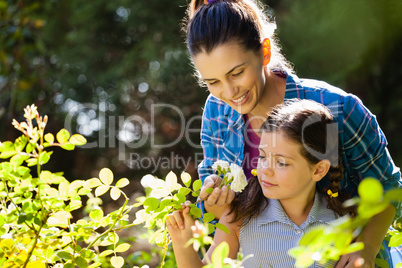 Smiling woman with daughter smelling white roses