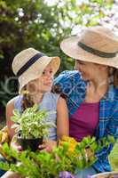 Smiling mother with daughter holding potted plant