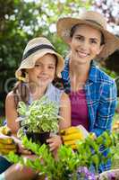 Portrait of smiling mother and daughter with potted plants