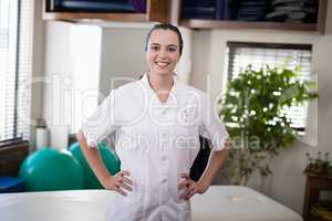 Portrait of smiling female therapist standing with hands on hip
