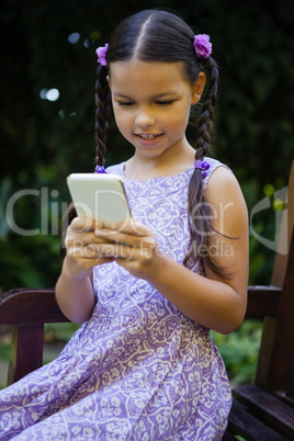 Girl using smartphone while sitting on bench