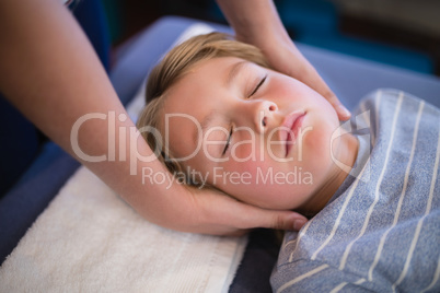 High angle view of boy with eyes closed receiving neck massage from female therapist
