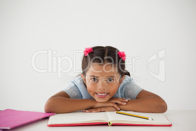 Young girl with her head on desk against white background