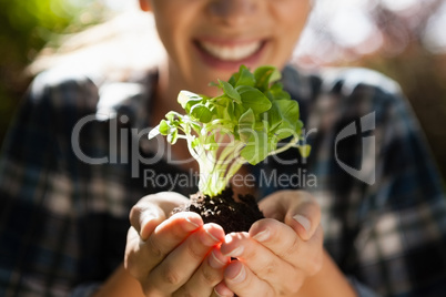 Mid section of smiling woman holding seedling