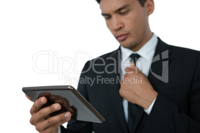 Businessman holding necktie while using tablet computer