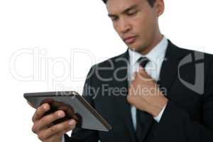 Businessman holding necktie while using tablet computer