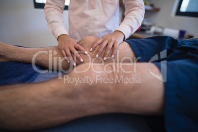 Female doctor massaging knee of patient