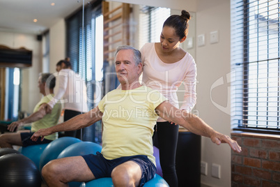 Female therapist looking at male patient exercising with arms outstretched