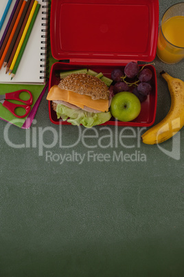 School supplies and lunch box arranged on chalkboard