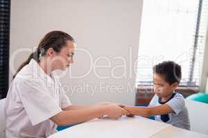 Boy looking while female therapist massaging wrist at table