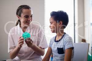 Smiling female therapist showing stress ball to boy