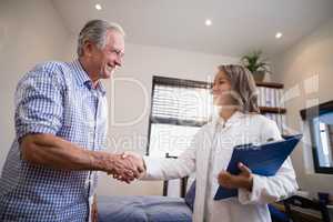 Smiling senior male patient and female therapist shaking hands