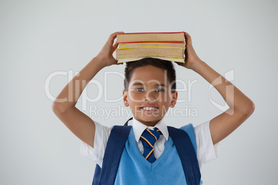 Schoolboy holding books on his head against white background
