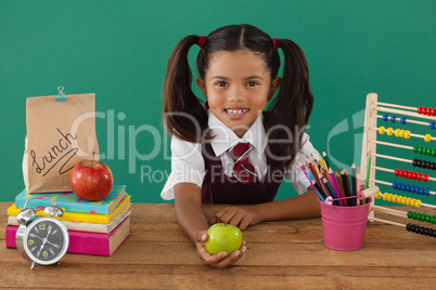 Schoolgirl holding a green apple against green background