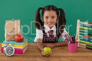 Schoolgirl holding a green apple against green background
