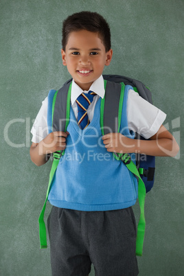 Schoolboy standing in front of chalkboard in classroom