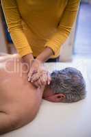 High angle view of female therapist giving neck massage to shirtless male patient