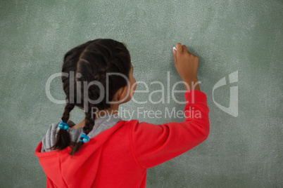 Young girl writing on chalk board