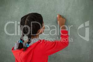Young girl writing on chalk board