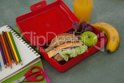 School supplies and lunch box arranged on chalkboard
